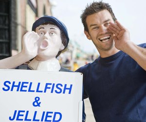 Shop vendor imitating mascot by seafood shop