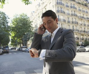 France, Paris, man using mobile phone in street, checking watch