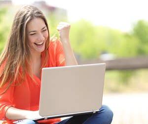 Euphoric woman searching job with a laptop in a park