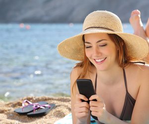 Woman on the beach texting a smart phone in summer