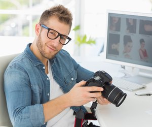 Handsome photographer holding his camera smiling at camera