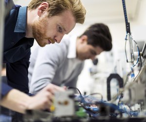 Two young handsome engineers working on electronics components