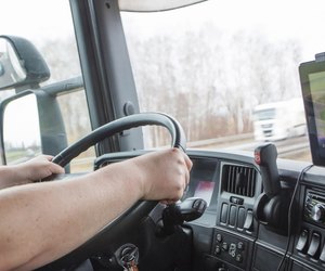 Male arms driving a truck on the road