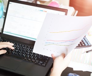 Hands of businesswoman holding analysis chart with laptop and ca