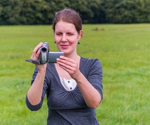 Young woman filming with a camcorder/ handycam