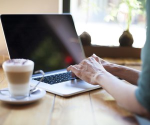 green shirt woman typing blank screen laptop