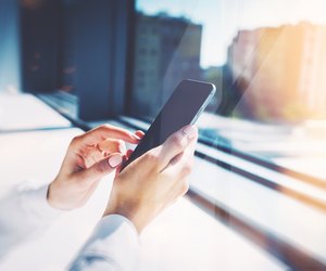 Girl touching a screen of her smarthone. Blurred background, horizontal
