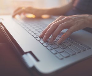 Woman working at home office hand on keyboard close up