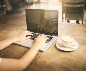 Girl typing on a laptop keyboard in a cafe