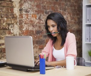 Woman siiting and holding a pencil in her mouth