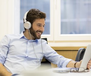 Cheerful man listening music and using computer in modern office