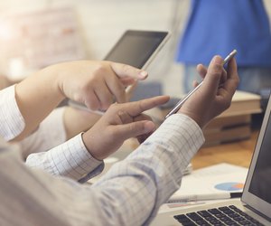 man's hand working with mobile phone, tablet, document and lapto