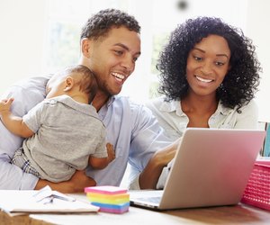 Parents With Baby Working In Office At Home