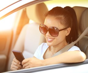 happy woman driver use her cell phone in car