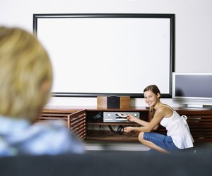 Side profile of a girl inserting a dvd into a dvd player