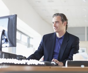 Businessman at desk in office, looking at monitor, low angle view