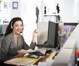 Businesswoman wearing headset at desk, smiling, portrait