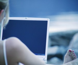 Woman works on lap top computer at the beach
