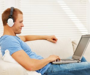 Smart young man listening to music while using a laptop