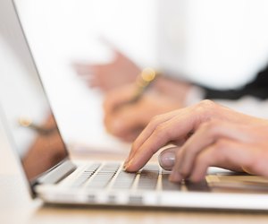 Woman using laptop in office during a meeting. Close-up hands