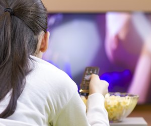 Relaxed teenage girl with remote control watching smart TV