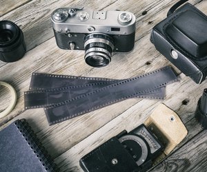 Old photo film, exposure meter and retro camera on background