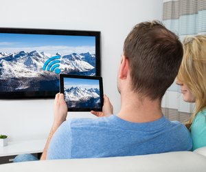 Couple With Digital Tablet And Television In Room