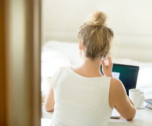 Woman sitting back talking on the phone at table.