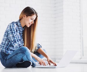 Happy student girl using laptop at home