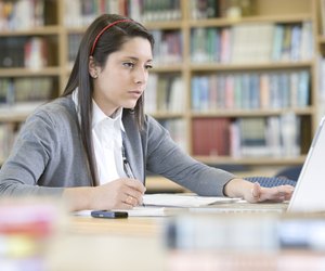 School girl (16-17) using laptop, working in library