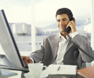 Young businessman using PC and phone