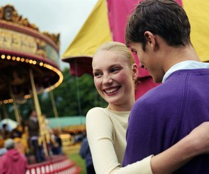 Young couple embracing at fairground, smiling, close-up