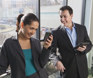 Business couple in office looking at tablet and smartphone