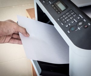 Hand holding paper sheets into printer tray