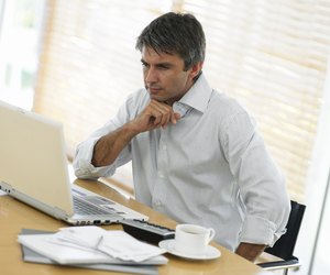 Man at desk, looking at laptop