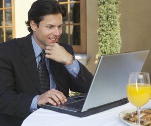 Mid adult business man working on laptop at outdoor cafe table