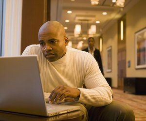 African businessman working on laptop in corridor