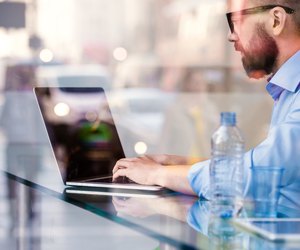 Hipster manager in cafe, working on laptop by window