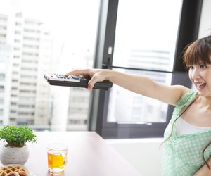 Young woman holding remote control, smiling