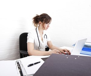 Young female doctor using laptop at desk in clinic
