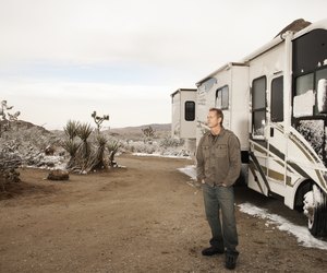 Man standing by motor home in desert with melting snow