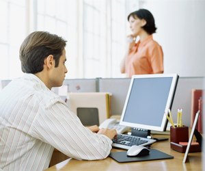 rear view of a businessman using a computer in an office cubicle