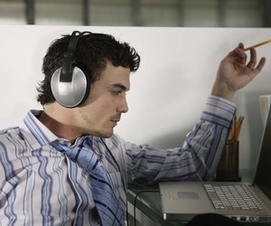 Businessman working at laptop while listening to music