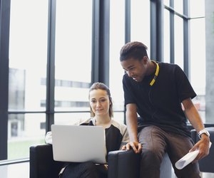 Two young students using laptop in campus