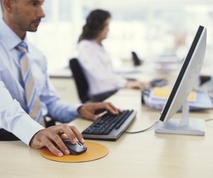Businessman using PC, hand on mouse, side view