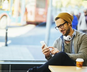 man typing text message in a coffee shop