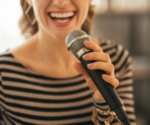 closeup on young woman singing with microphone in loft apartment