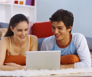 Portrait of a young couple lying on the floor and viewing a laptop
