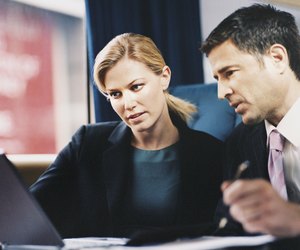 Two Business Executives Sitting on a Passenger Train and Working on a Laptop