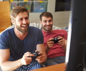 Two Male Friends In Pajamas Playing Video Game Together